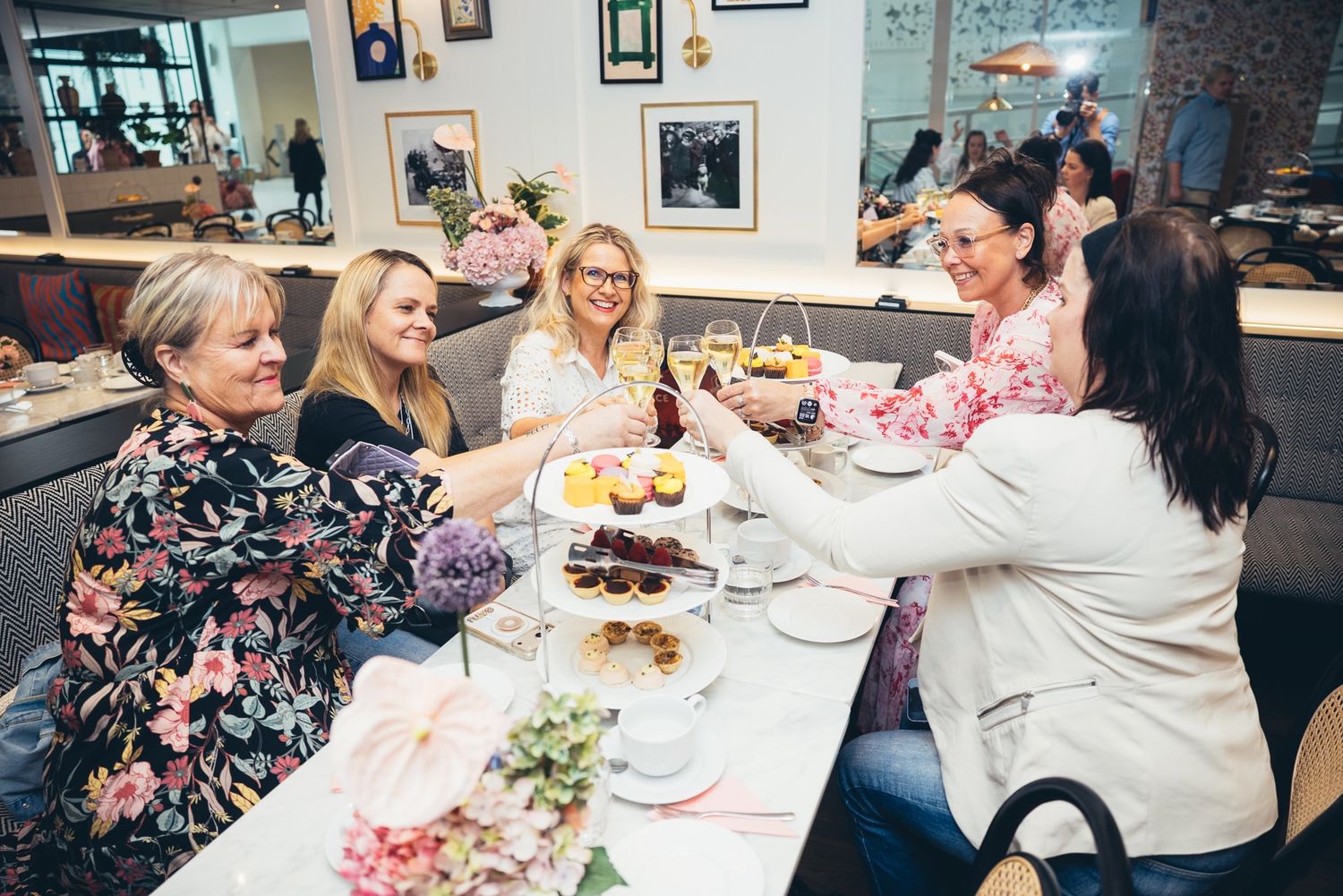 Vieraat nostavat maljan afternoon tea -pöydässä