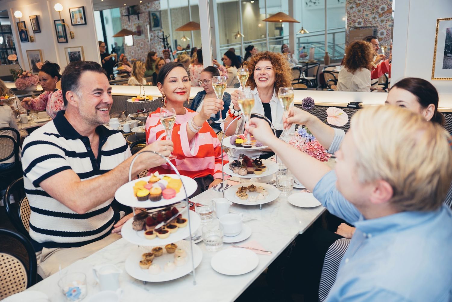 Vieraat maljan nostossa afternoon tea -tarjoilujen äärellä