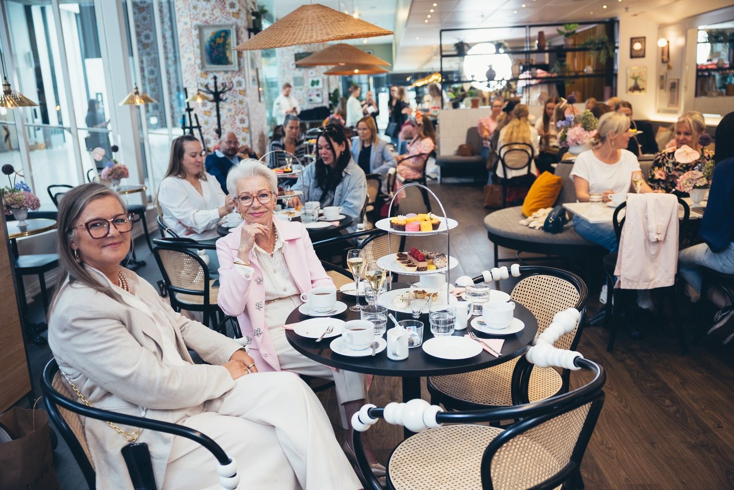 Vieraita pöydässä kolmikerroksisen tarjoilutelineen äärellä