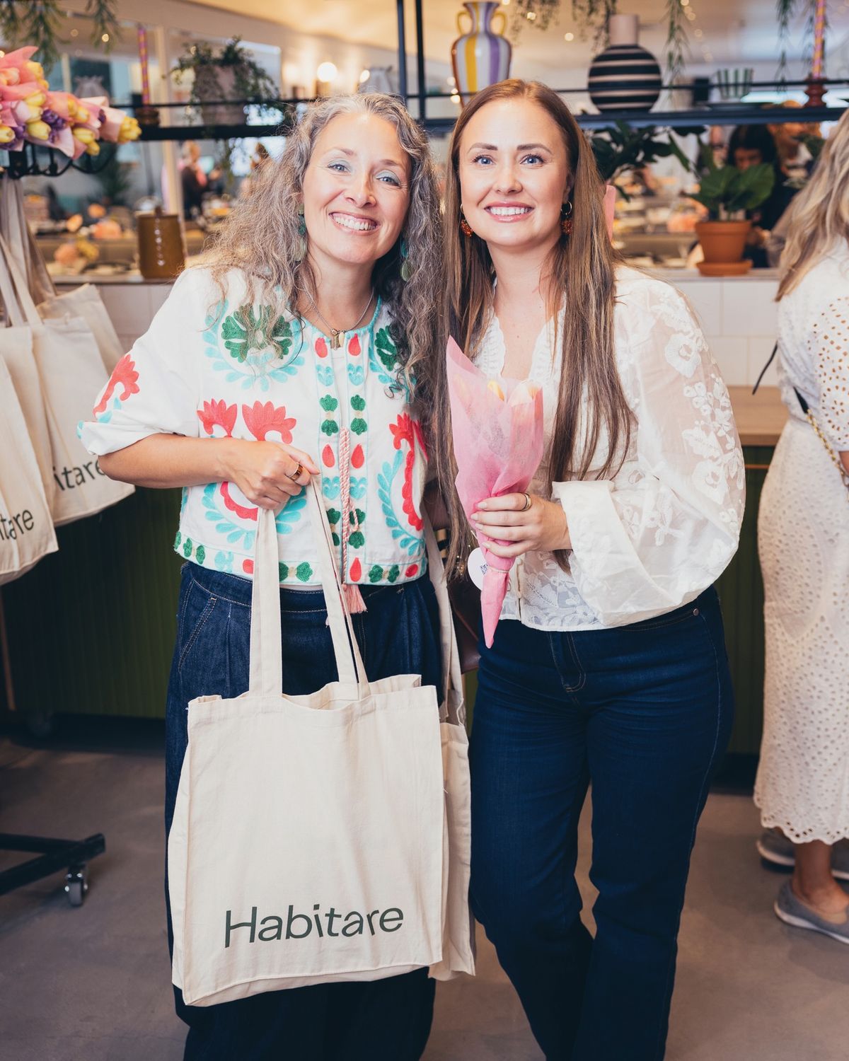 Kaksi vierasta poseeraamassa give away -lahjojen kanssa
